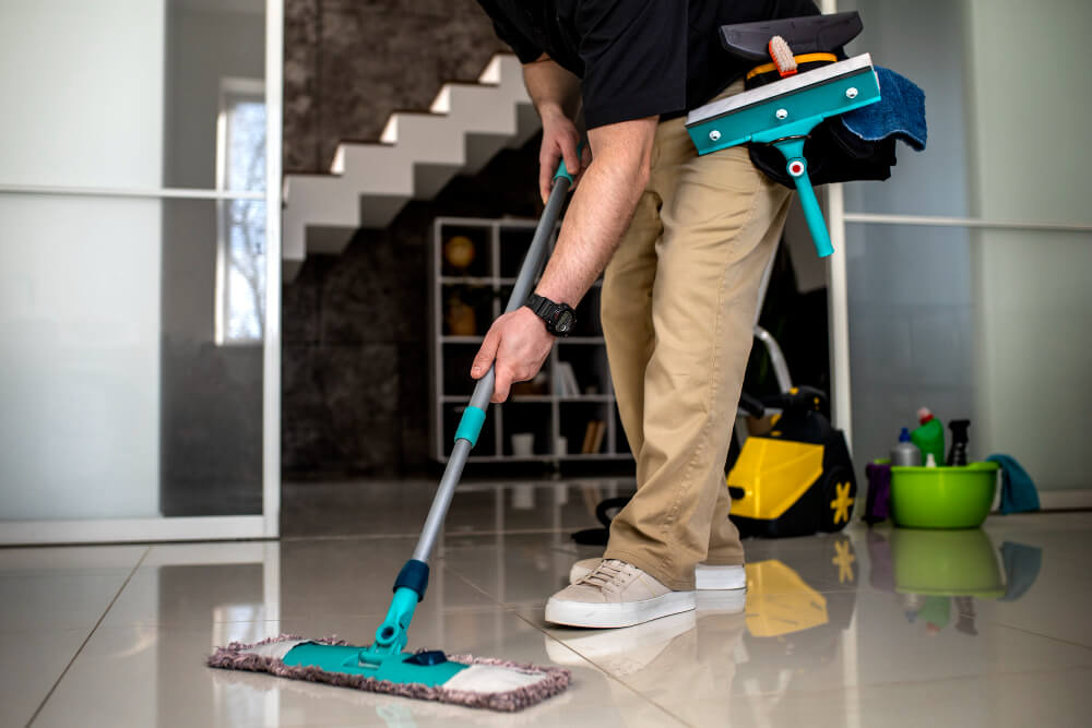 a person using an industrial mop to clean the floors of a building. there are stairs in the background
