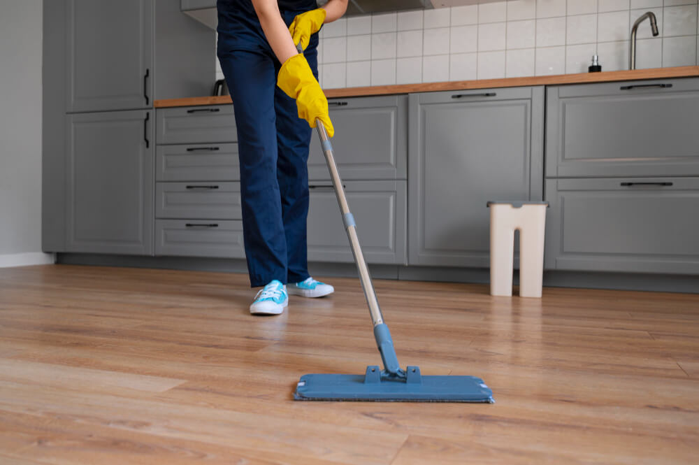 image of someone cleaning kitchen floors with a dust mop
