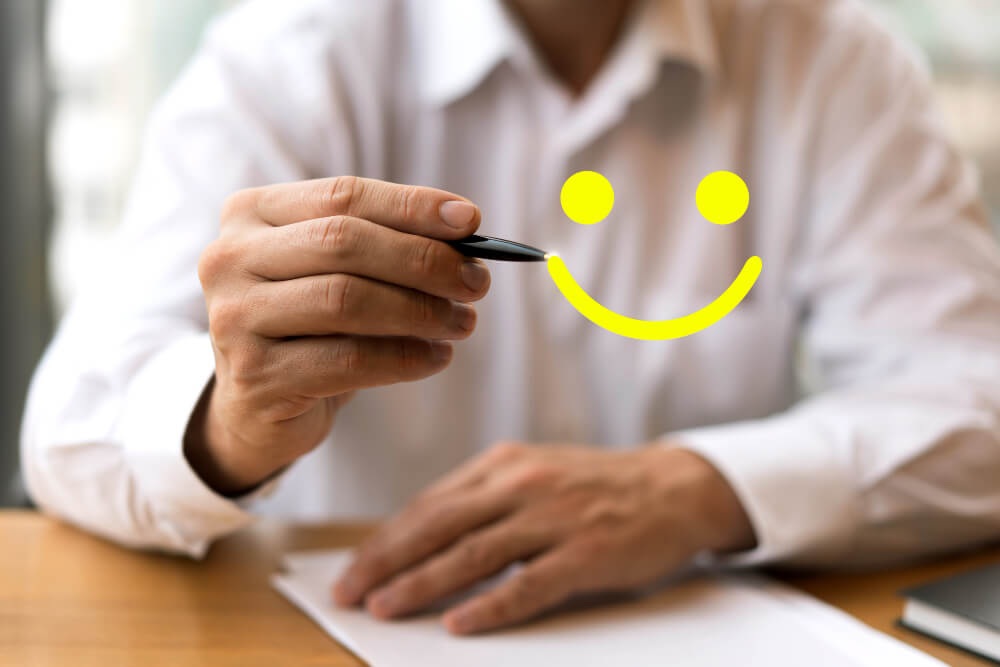 smiley emoji on the foreground of a man seemingly writing the emoji on the screen