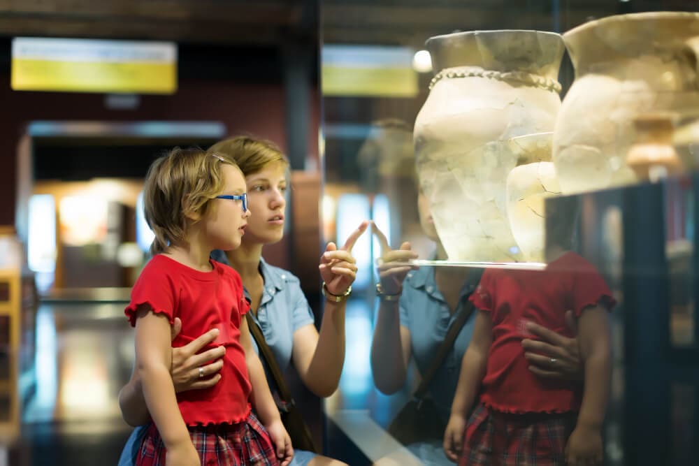 mother pointing out something to daughter in a museum display case