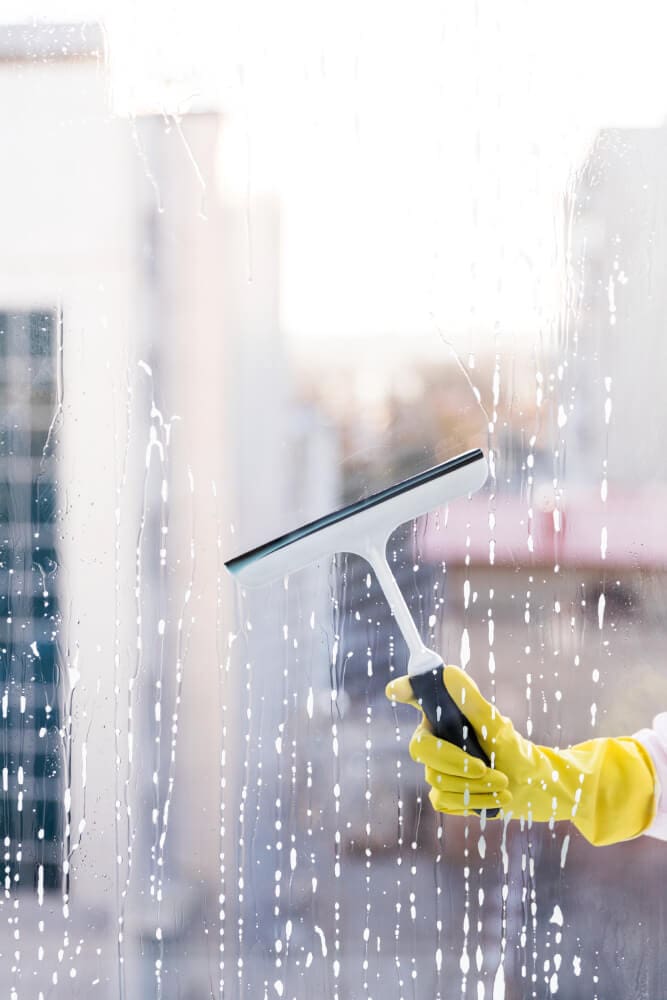 person wearing yellow gloves holding a squeegee