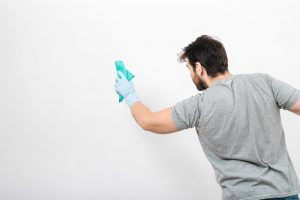 Concept of man cleaning his home with copyspace on wall