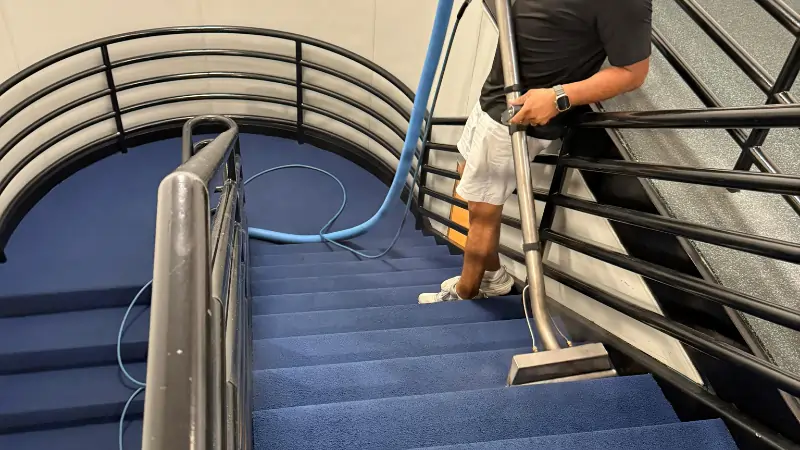 Carpet cleaning - Cleaner vacuuming carpet floor on staircase in Arlington TX office facility