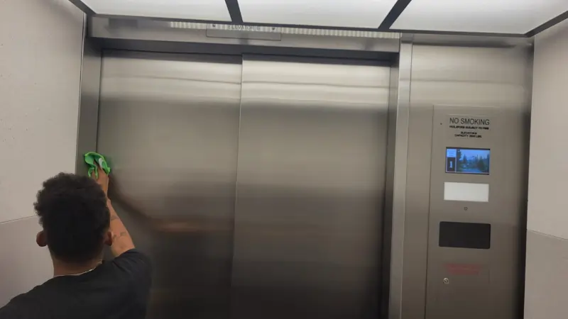 Craddocks Day Porter Cleaning metal surfaces in elevator in Arlington TX office building