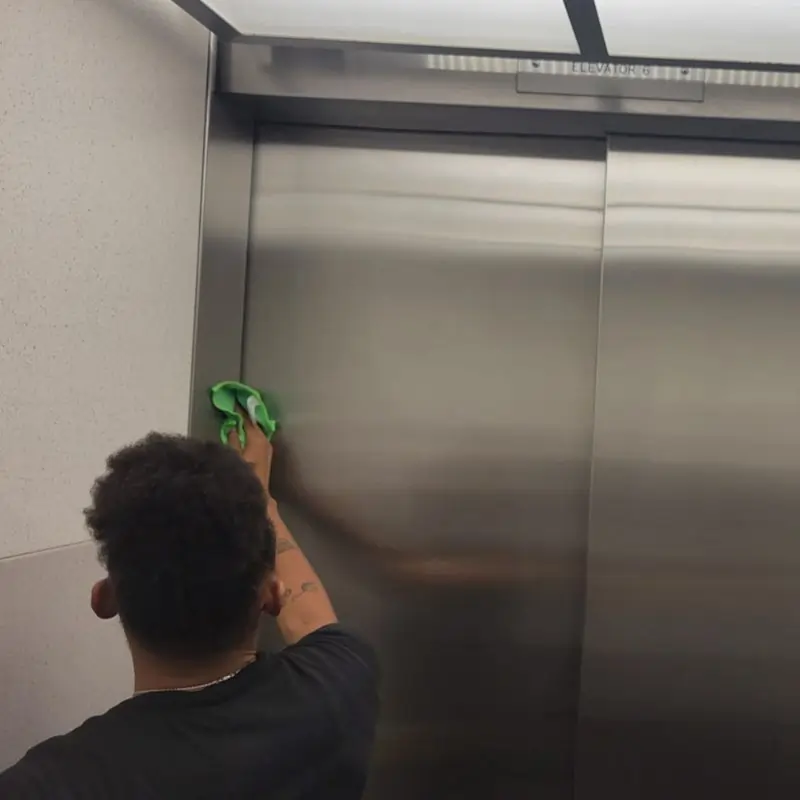 Day porter cleaning elevator and metal surfaces in office building Day porter cleaning elevator and metal surfaces in office building