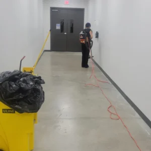 Before - Post construction cleaning of 100,000 sq ft Warehouse facility in Arlington TX - vacuuming construction dust in concrete floor hallway