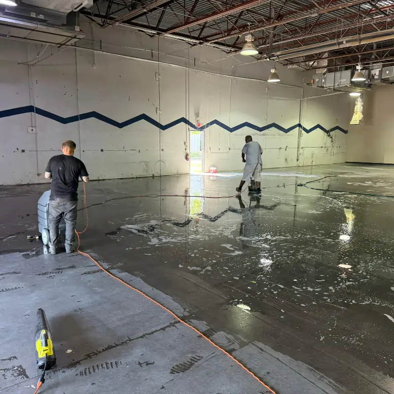 Crew cleaning and polishing cement floors in warehouse facility Crew cleaning and polishing cement floors in warehouse facility