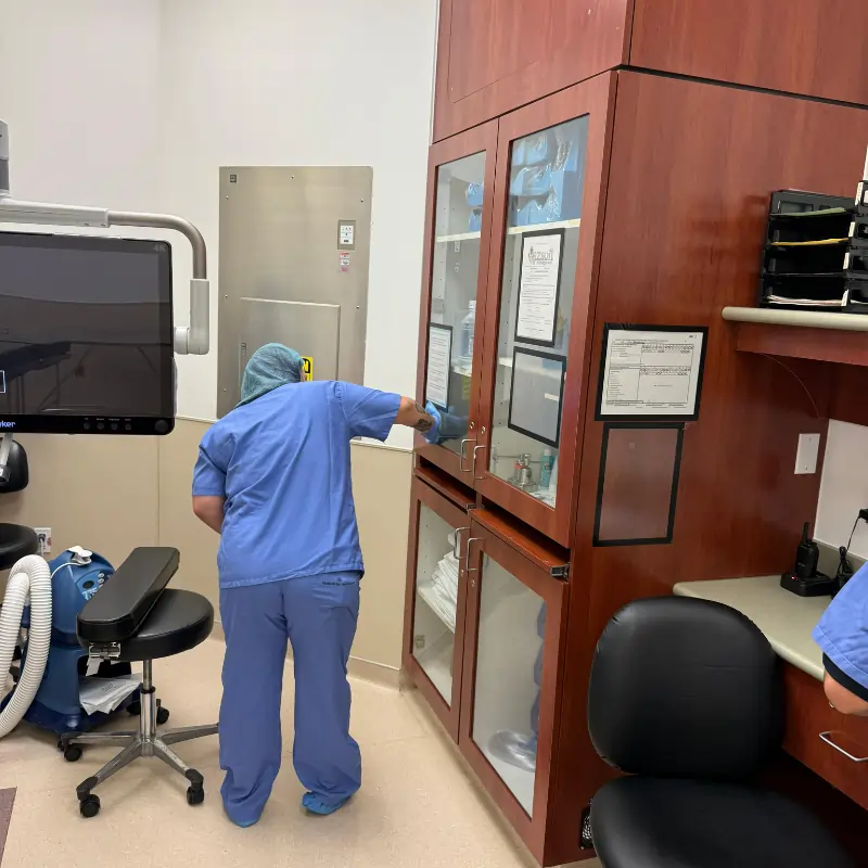 Crew cleaning the nurse desk and glass cabinets in medical facility